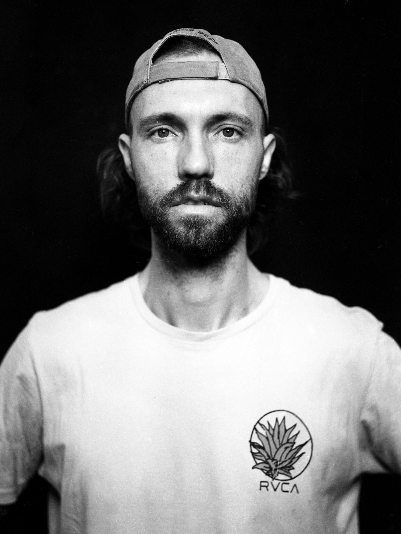 A finished 4x5 close portrait of a man in a cap against a black background