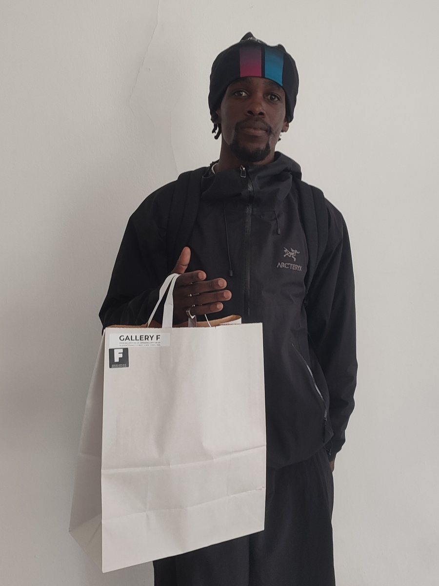 A client in a black jacket and beanie holding a paper bag with his starter kit