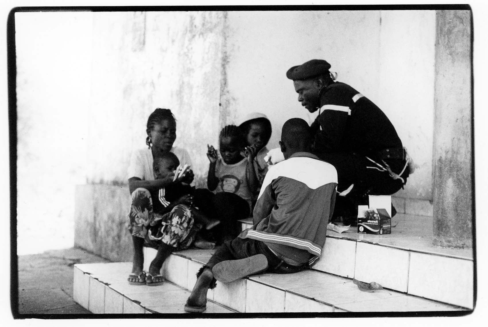 A black and white print of children and a man in a beret sitting on tiled steps
