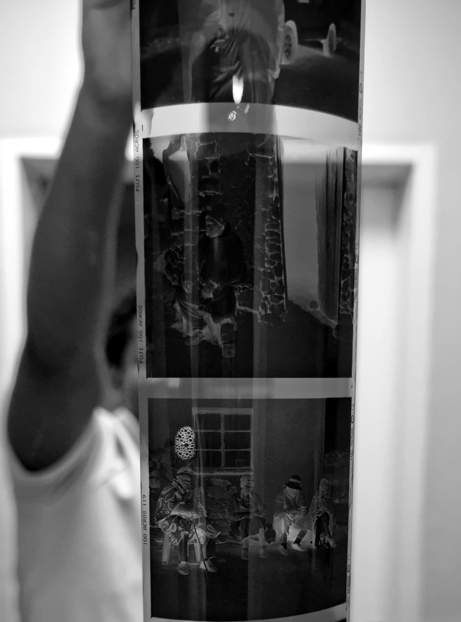 A hand holding up a long strip of freshly developed 120 negatives